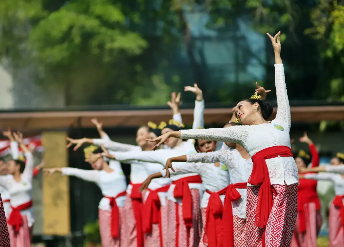 A group of women performing a traditional Indonesian dance in cultural attire outdoors.