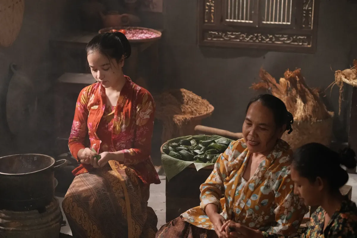 Women in traditional attire preparing food indoors in Jakarta, Indonesia.