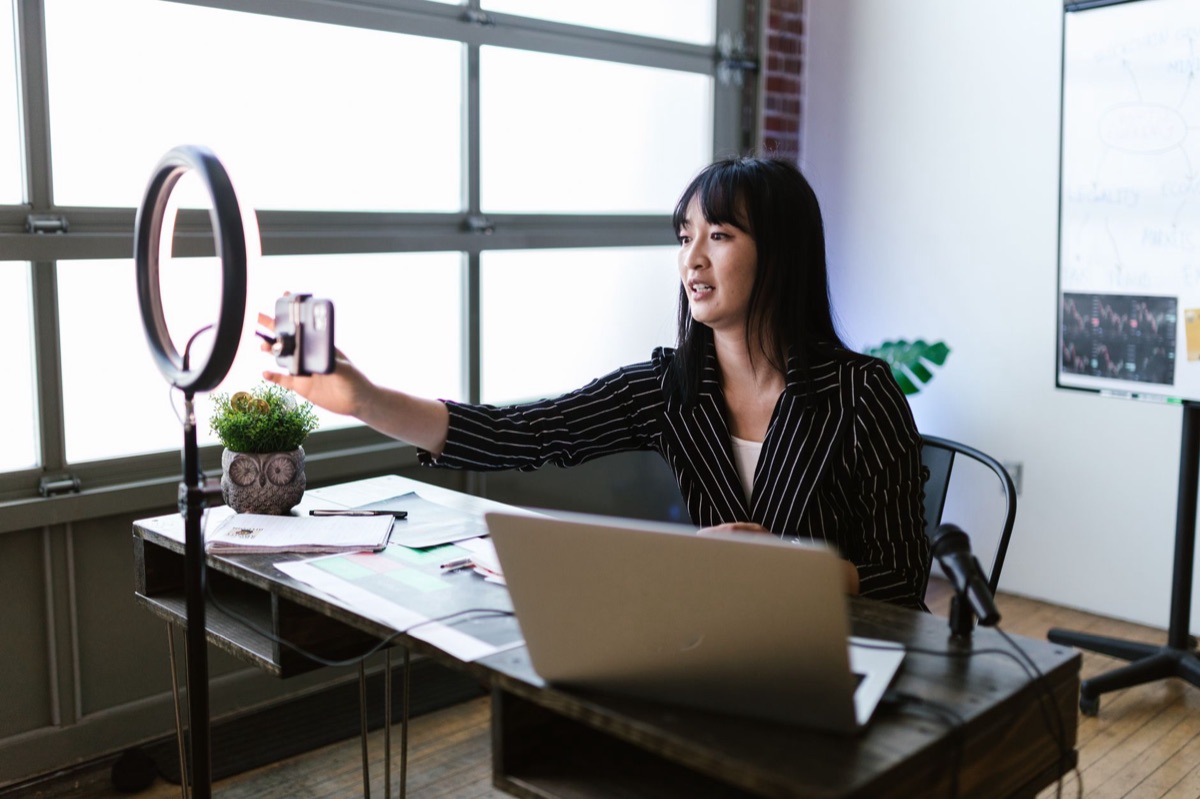 influencer indonesiana com laptop e celular em mesa