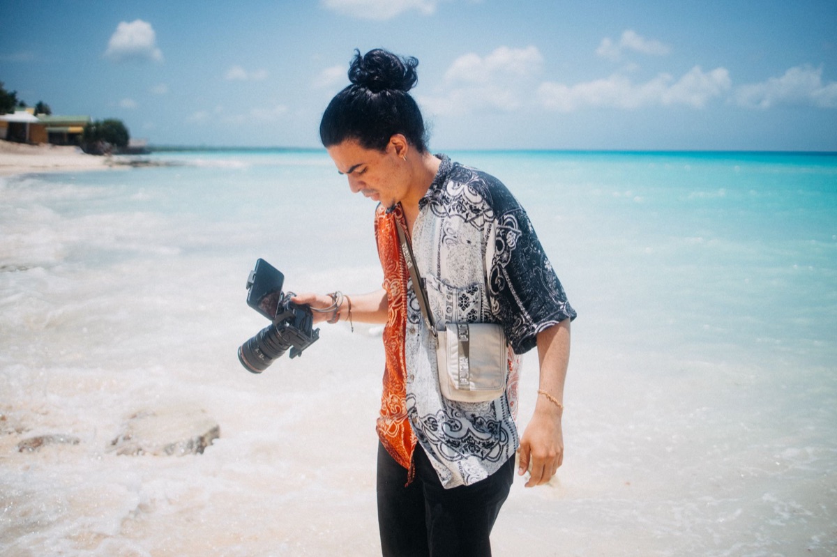 Un influencer indonesio en una playa tropical con cámara