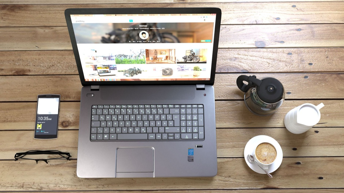 influencer indonesiana com laptop e celular em mesa de madeira