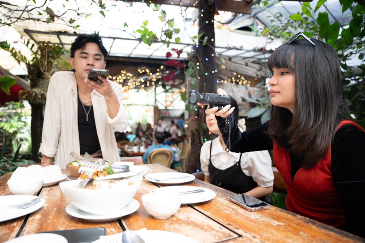 Celebrità indonesia che filma un vlog con smartphone in ambiente urbano