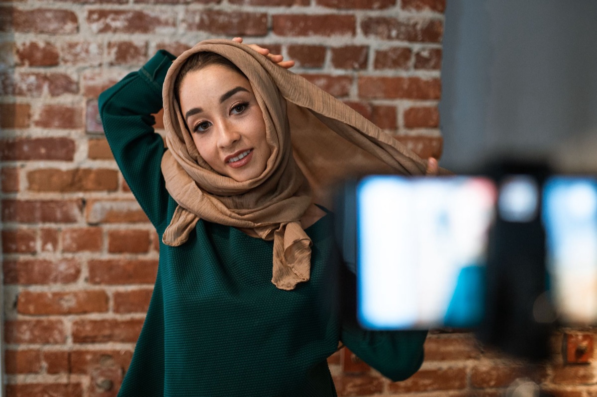 Indonesian influencer filming outdoors with natural background and equipment