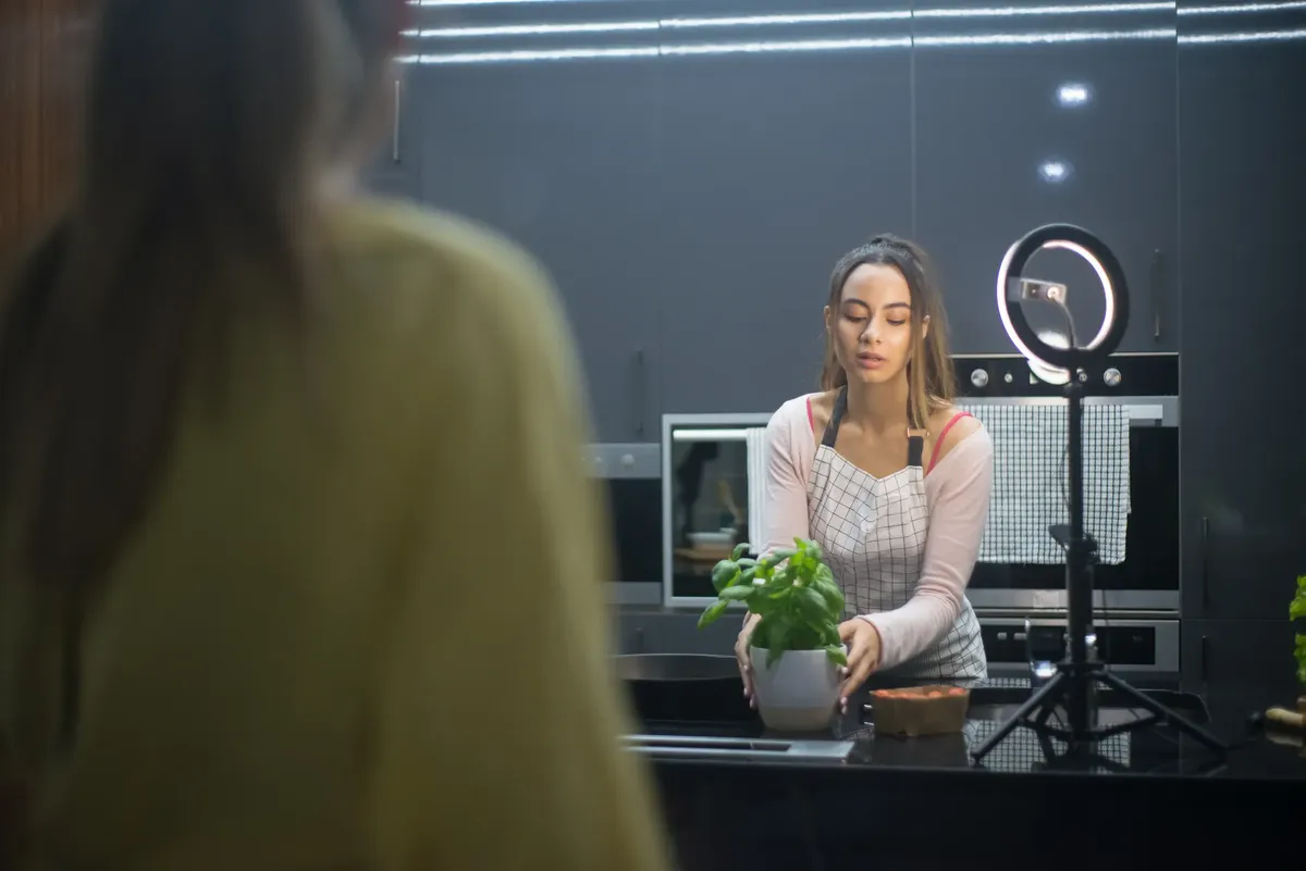 A woman arranging a potted plant on a kitchen counter, set for content creation.