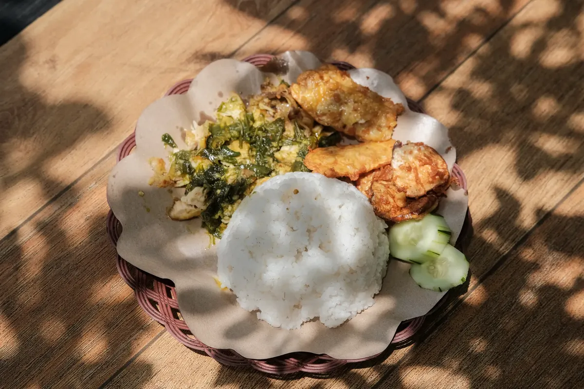 Enjoy a delicious plate of Indonesian Ayam Geprek with rice, tempeh, and cucumber.