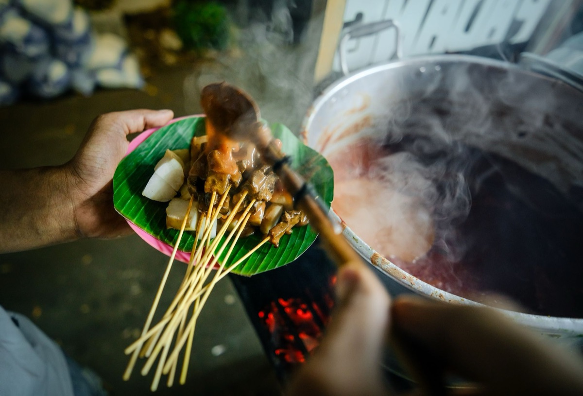 un chef indonesio con un piatto di saté